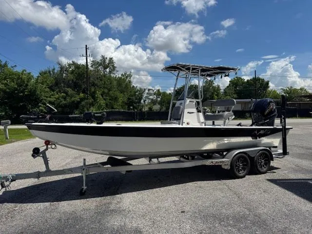 Slide: The Image of 2025 Avid 23 Mag boat on trailer, parked outdoors under a cloudy sky. - 2