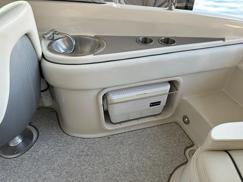 Slide: The Image of Interior of 2010 Sea Ray 240 Sundeck with sink, cup holders, and cooler storage. - 21