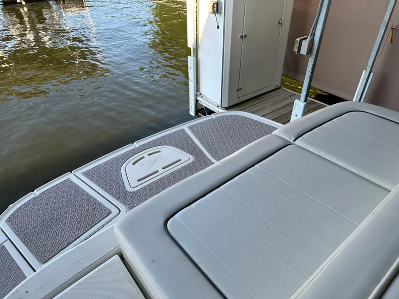 Slide: The Image of 2010 Sea Ray 240 Sundeck boat with cushioned seating and swim platform by the water. - 25