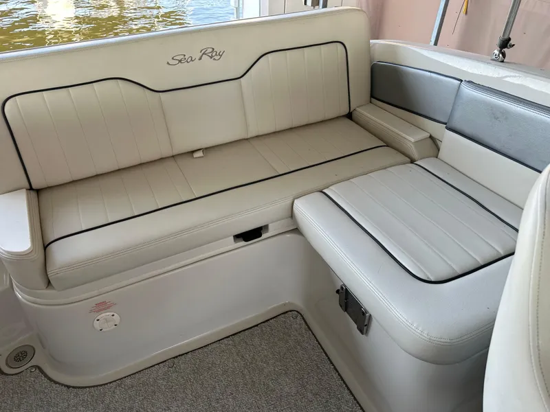 Slide: The Image of 2010 Sea Ray 240 Sundeck boat interior seating with white upholstery and black trim. - 9