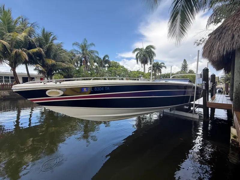 Slide: The Image of 1988 Wellcraft Scarab 38 KV boat docked by palm trees, reflecting on calm water. - 16