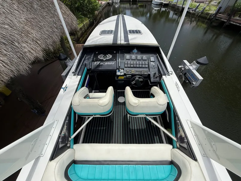 Slide: The Image of 1988 Wellcraft Scarab 38 KV boat interior with dual seats and control panel, docked by water. - 19