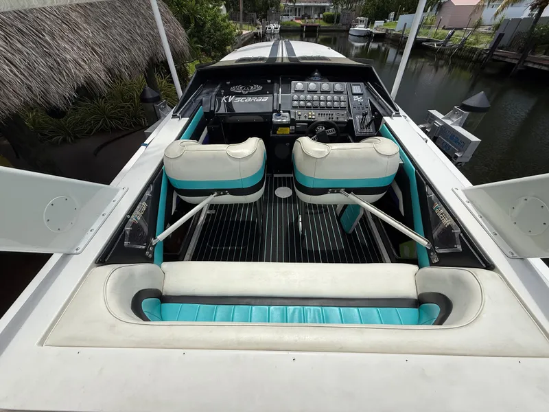 Slide: The Image of 1988 Wellcraft Scarab 38 KV boat interior with teal and white seating, docked by a canal. - 20