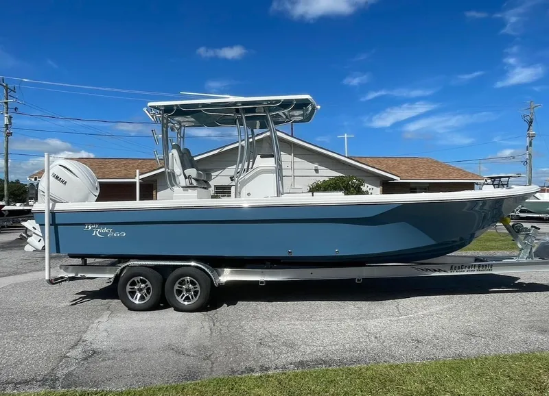 The Image of 2026 Bay Rider 269 Bay boat on trailer, blue hull, clear sky background. - 1