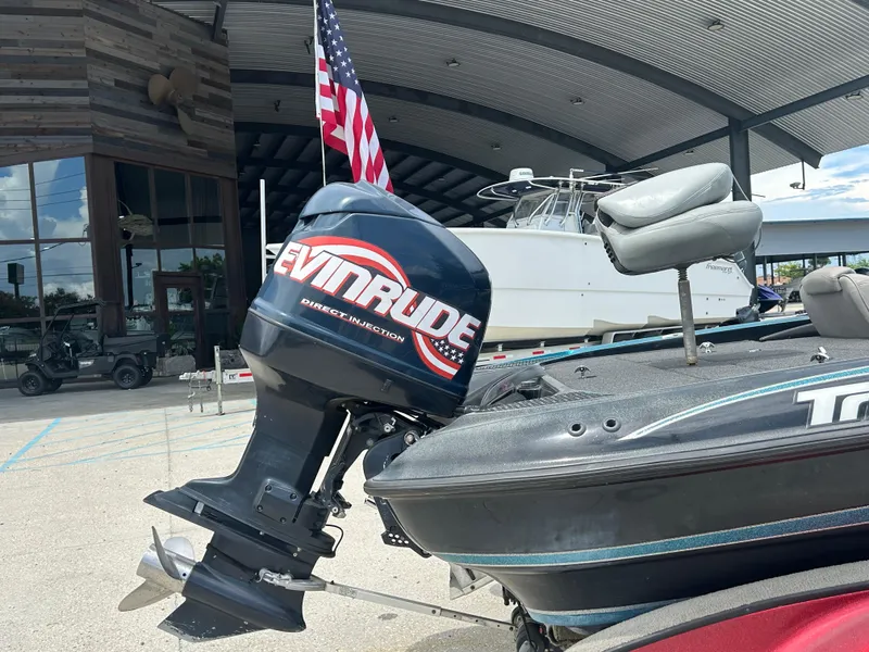 Slide: The Image of 2004 Triton Tr-20XDC boat with Evinrude outboard motor, parked near a building. - 3