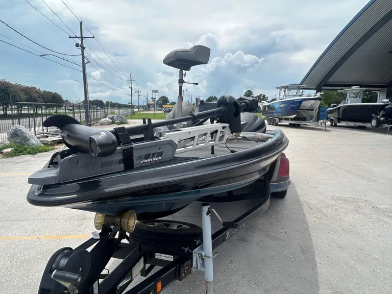 Slide: The Image of 2004 Triton Tr-20XDC boat on trailer, parked outdoors near other boats. - 4