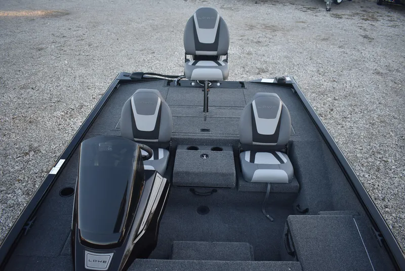 Slide: The Image of 2025 Lowe Stinger 175 boat interior with three seats and motor, on gravel surface. - 10
