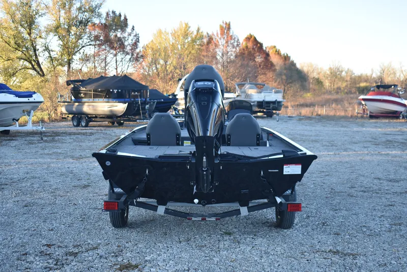 Slide: The Image of 2025 Lowe Stinger 175 boat on gravel lot, surrounded by trees and other boats. - 6