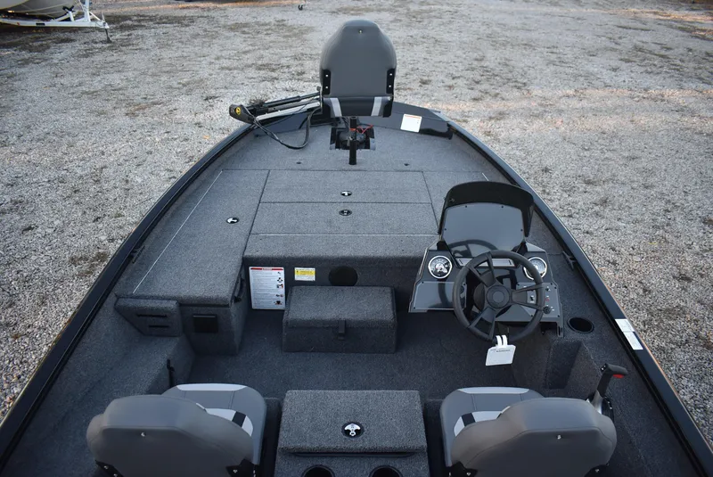 Slide: The Image of 2025 Lowe Stinger 175 boat interior with steering wheel and seating, on gravel surface. - 8