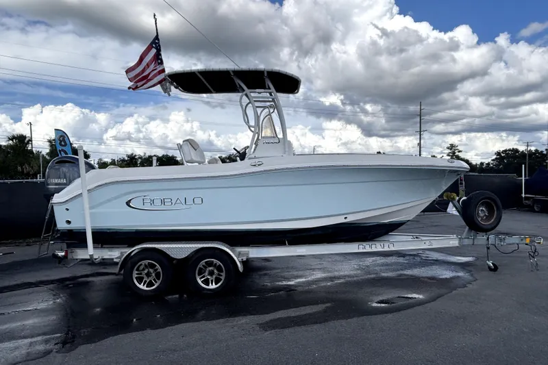 Slide: The Image of 2017 Robalo R200 Center Console boat on trailer with American flag, under cloudy sky. - 1