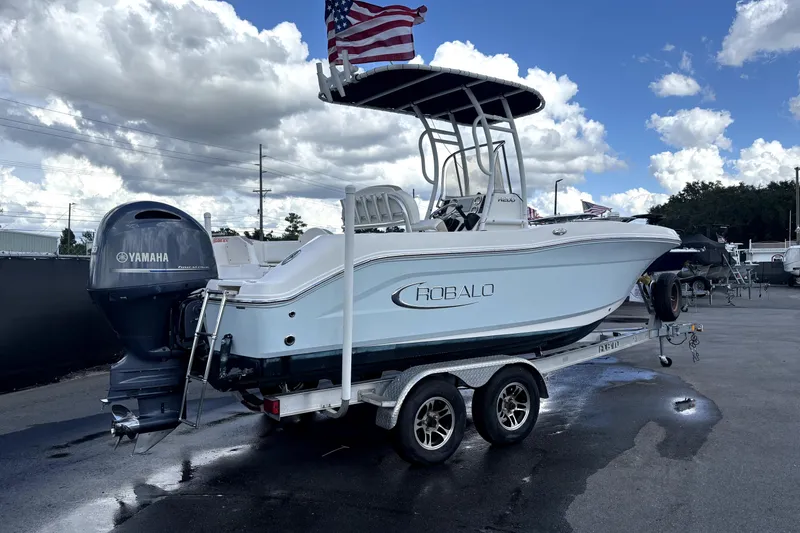 Slide: The Image of 2017 Robalo R200 Center Console boat on trailer with Yamaha engine, under cloudy sky. - 2
