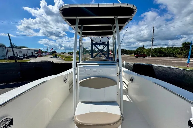 Slide: The Image of 2017 Robalo R200 Center Console boat with T-top, parked outdoors under a blue sky. - 29