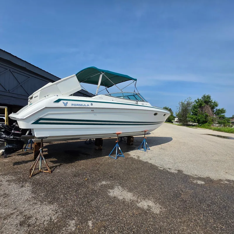 Slide: The Image of 1998 Formula 33 Super Sun Sport boat on stands, blue canopy, clear sky background. - 14