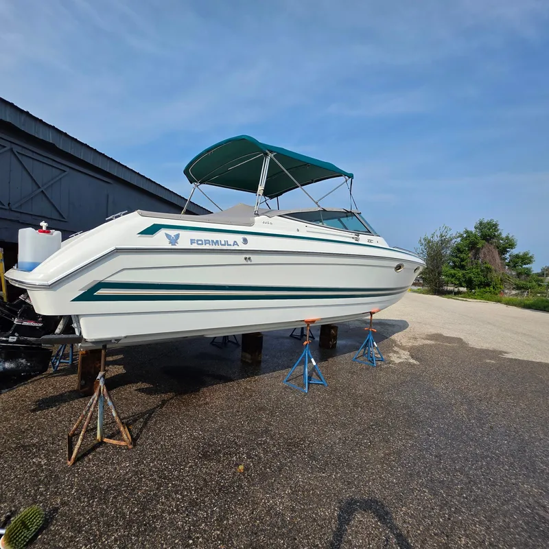 Slide: The Image of 1998 Formula 33 Super Sun Sport boat on stands, with blue canopy, outdoors. - 15