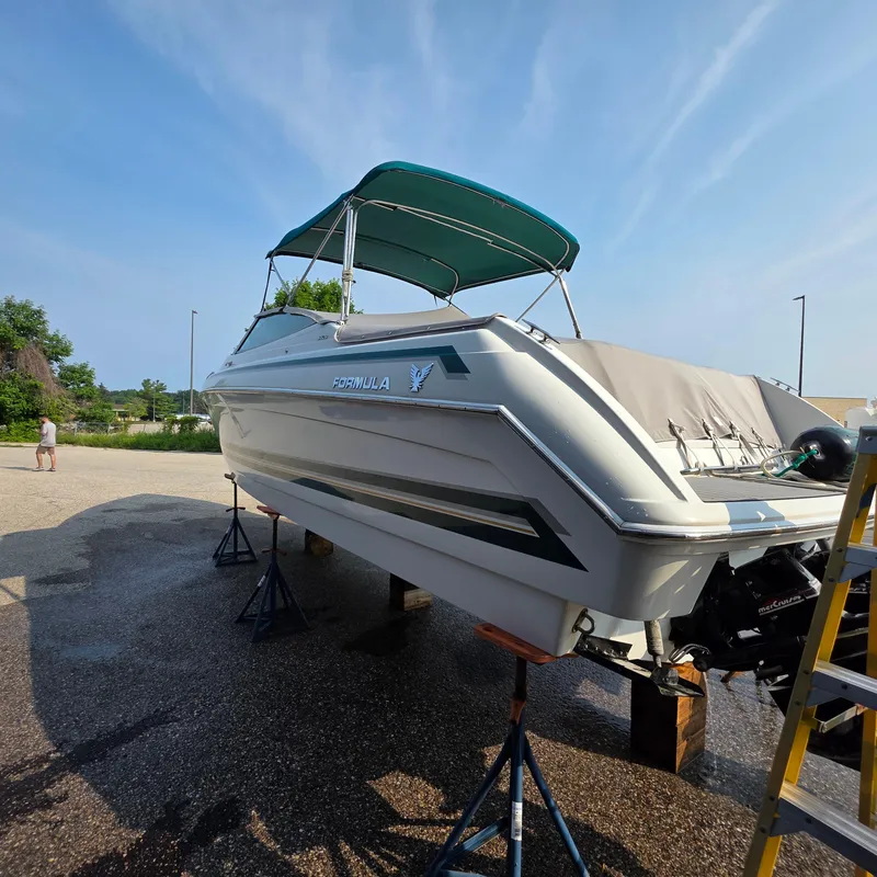Slide: The Image of 1998 Formula 33 Super Sun Sport boat on stands, with blue canopy, in outdoor setting. - 16