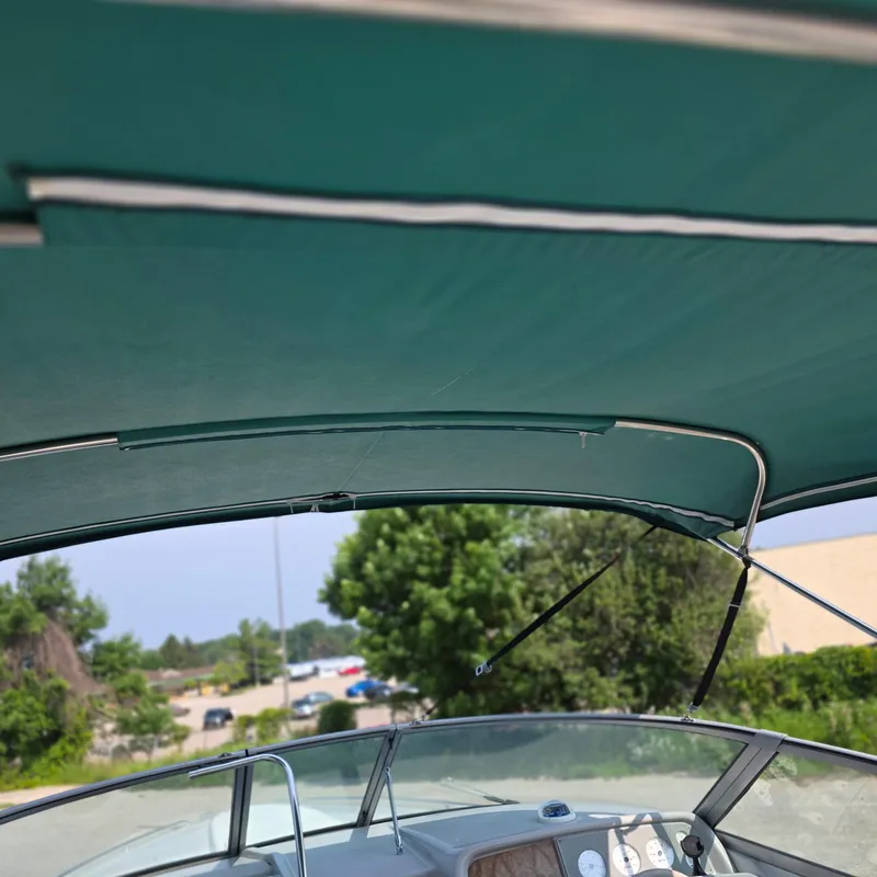 Slide: The Image of 1998 Formula 33 Super Sun Sport boat with green canopy and dashboard view. - 27