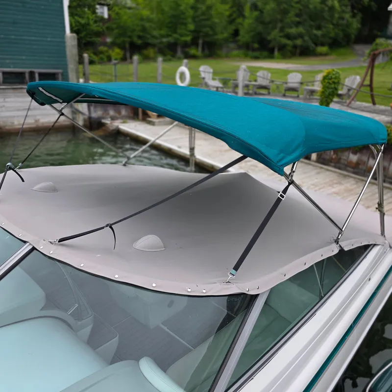 Slide: The Image of 1998 Formula 33 Super Sun Sport boat with teal canopy docked by a lakeside. - 5