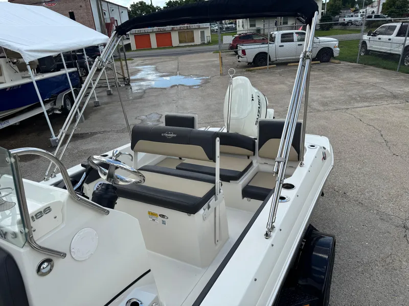 Slide: The Image of 2019 Stingray 186 CC boat with seating and steering wheel, parked outdoors. - 17