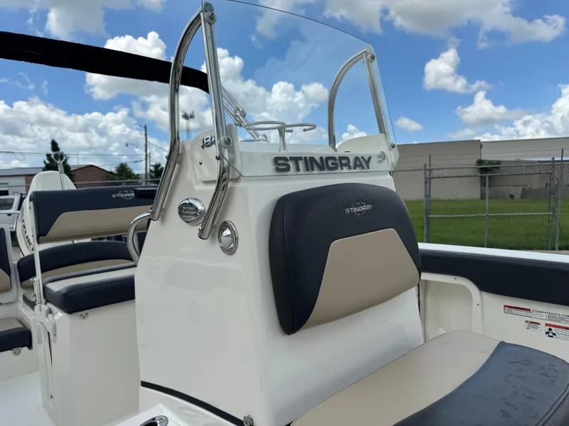 Slide: The Image of 2019 Stingray 186 CC boat interior with seating and console, under a partly cloudy sky. - 19
