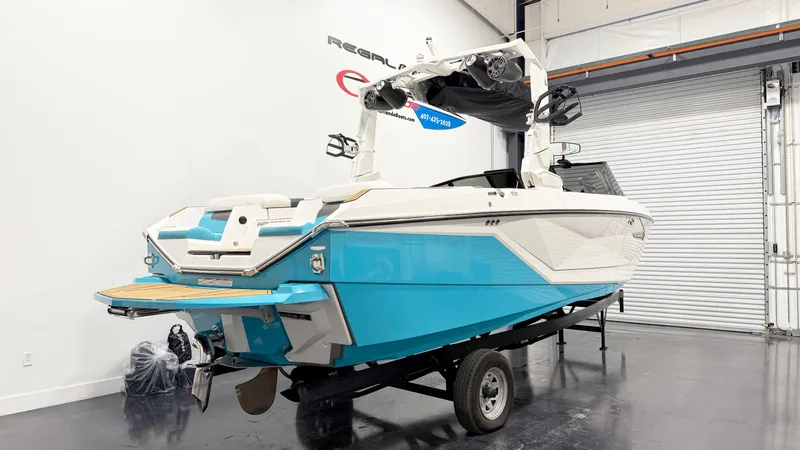 Slide: The Image of 2022 Nautique G23 boat in showroom, blue and white design, on trailer. - 3