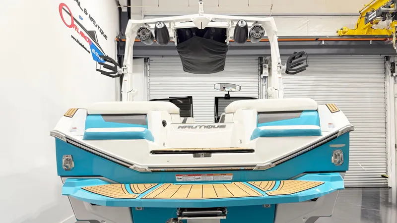 Slide: The Image of 2022 Nautique G23 boat in showroom, rear view, blue and white design. - 4