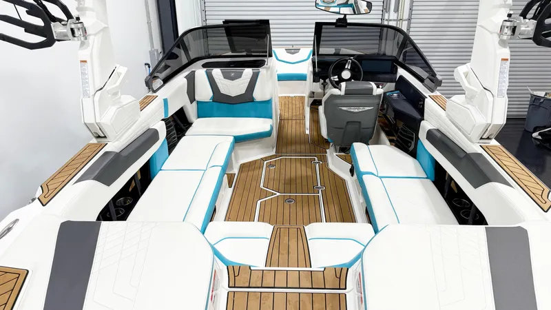 Slide: The Image of 2022 Nautique G23 boat interior with white and teal seating, wooden flooring, and modern dashboard. - 6