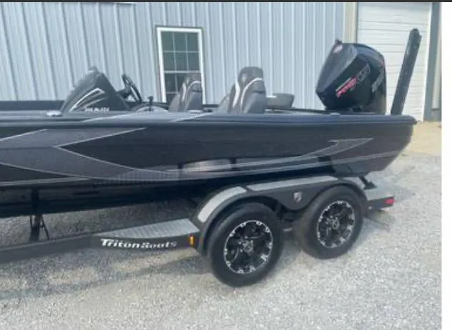 Slide: The Image of 2022 Triton 21 XrT boat on trailer, sleek black design, parked near a building. - 4