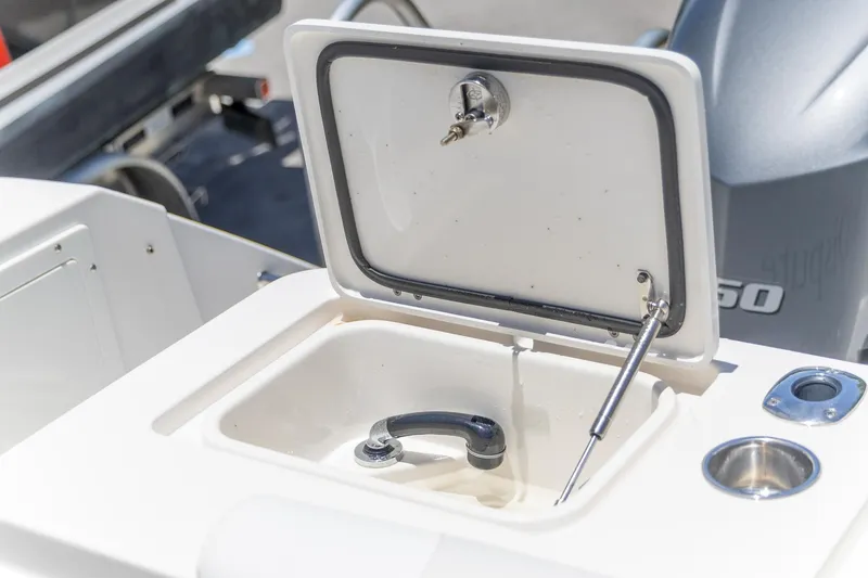 Slide: The Image of Open storage compartment on 2015 Edgewater 280 CX boat, featuring a secure latch and hydraulic support. - 24