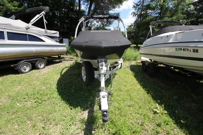 Slide: The Image of 2008 MasterCraft X-15 SS boat on trailer, parked between two other boats. - 2