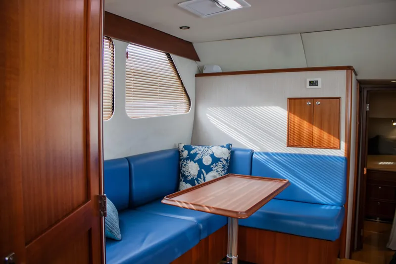 Slide: The Image of Interior of 2015 Huckins 45 yacht with blue seating and wooden table. - 24