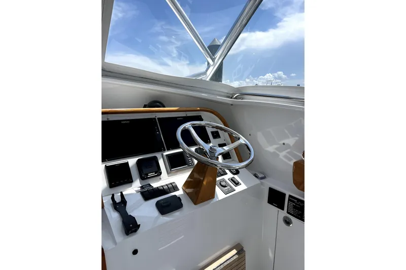 Slide: The Image of Helm of 2015 Huckins 45 yacht with modern controls and steering wheel under blue sky. - 28