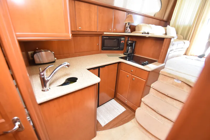Slide: The Image of 2007 Silverton 38 Convertible yacht kitchen with wood cabinetry, sink, microwave, and stairs. - 24