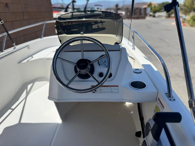 Slide: The Image of 2021 Boston Whaler 130 Super Sport boat dashboard with steering wheel and controls. - 14