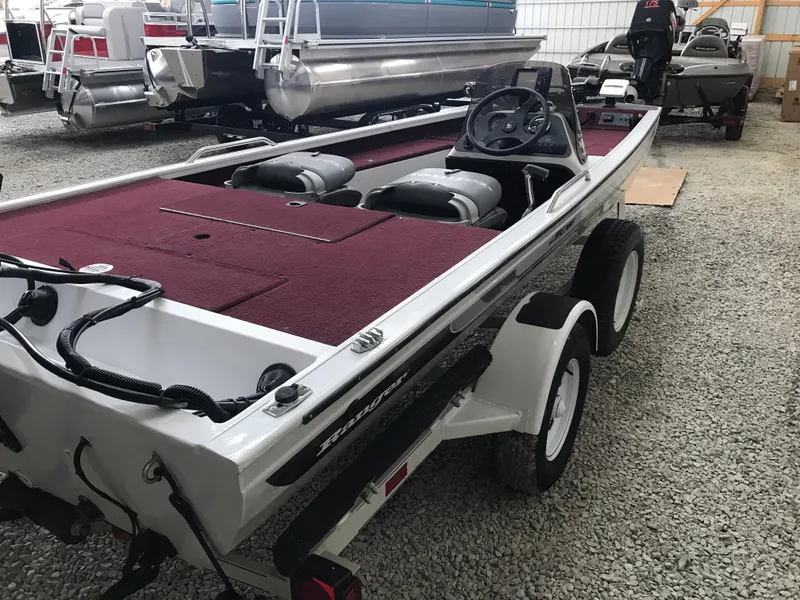 Slide: The Image of 1995 Ranger Cherokee 17' boat with maroon interior, parked on gravel near pontoon boats. - 4