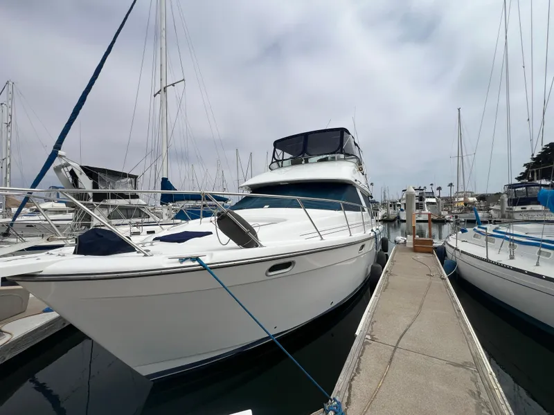 The Image of 1999 Bayliner 3988 Command Bridge Motoryacht docked at marina, overcast sky. - 0