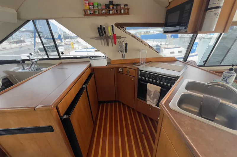 Slide: The Image of 1999 Bayliner 3988 Command Bridge Motoryacht kitchen with wooden cabinetry and modern appliances. - 20