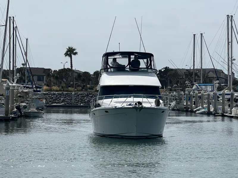 Slide: The Image of 1999 Bayliner 3988 Command Bridge Motoryacht docked in a marina, surrounded by sailboats. - 3