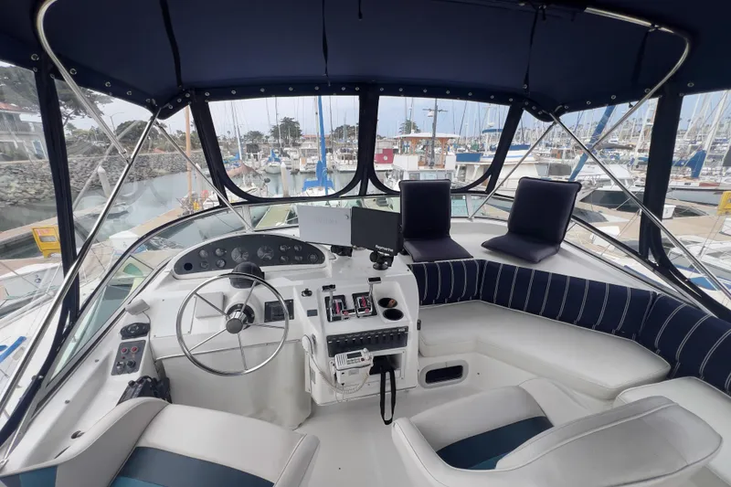 Slide: The Image of 1999 Bayliner 3988 Command Bridge Motoryacht helm with marina view, featuring modern controls. - 4