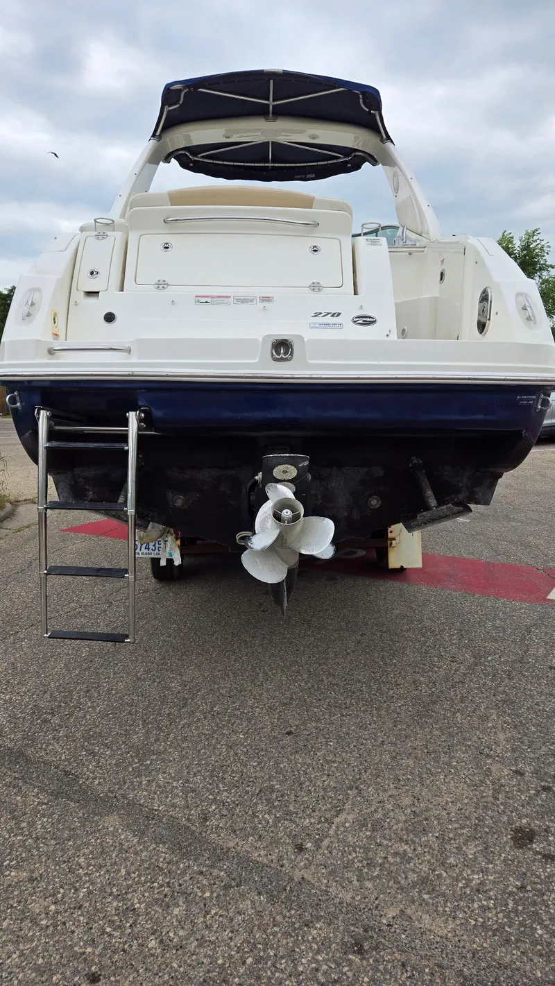 Slide: The Image of 2009 Sea Ray 270 Sundancer boat, rear view with ladder and propeller, parked on pavement. - 4