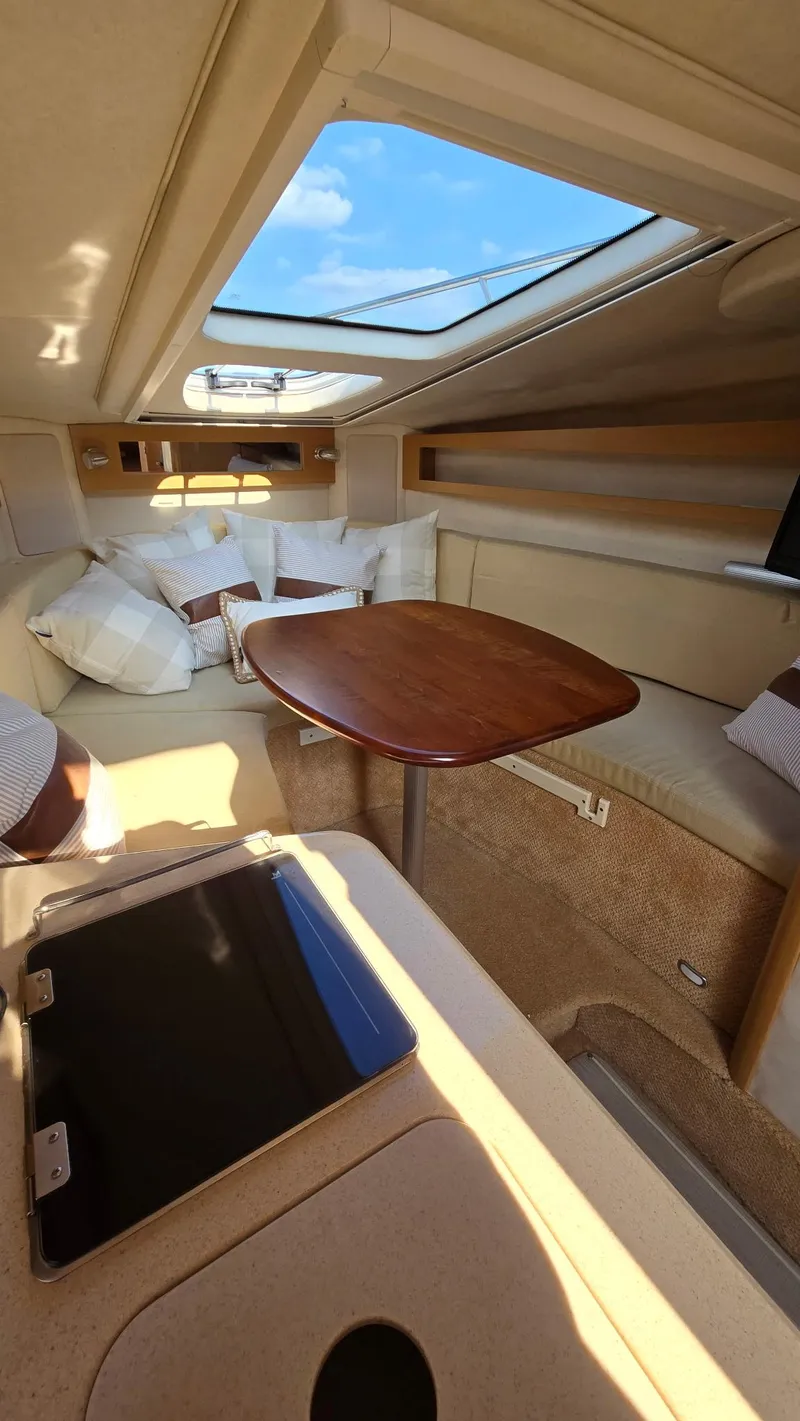Slide: The Image of Interior of 2009 Sea Ray 270 Sundancer with skylight, seating, and wooden table. - 7