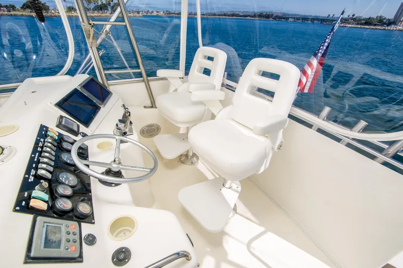 Slide: The Image of 1999 Riviera 43 Open Flybridge helm with dual white captain chairs and ocean view. - 11