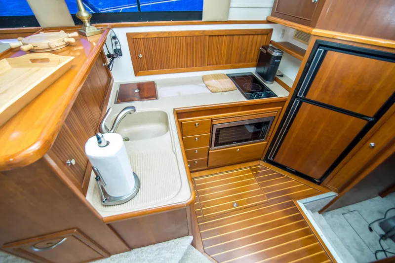 Slide: The Image of Luxurious 1999 Riviera 43 Open Flybridge yacht kitchen with wood cabinetry and modern appliances. - 25