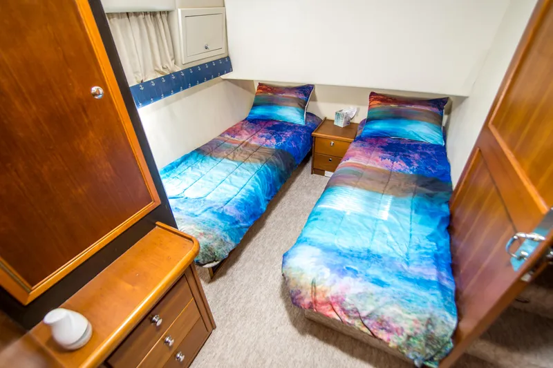 Slide: The Image of Twin beds in a 1999 Riviera 43 Open Flybridge cabin with colorful bedding. - 28