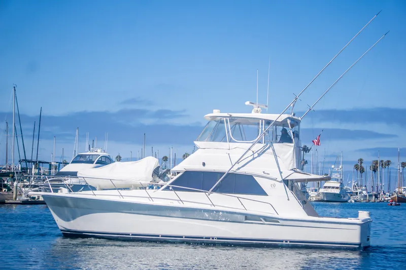 Slide: The Image of 1999 Riviera 43 Open Flybridge yacht in marina, clear blue sky, calm waters. - 3