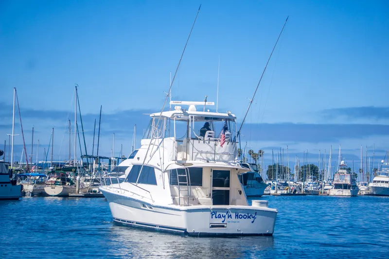 Slide: The Image of 1999 Riviera 43 Open Flybridge yacht in marina, clear blue sky, "Play'n Hooky" on stern. - 4