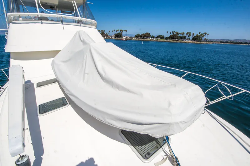 Slide: The Image of 1999 Riviera 43 Open Flybridge yacht with covered equipment on deck, overlooking serene waters. - 8