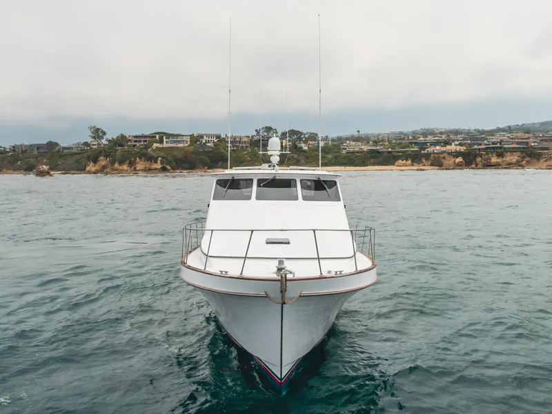 Slide: The Image of 1984 Vic Franck pilothouse yacht on calm waters near a coastal landscape. - 2