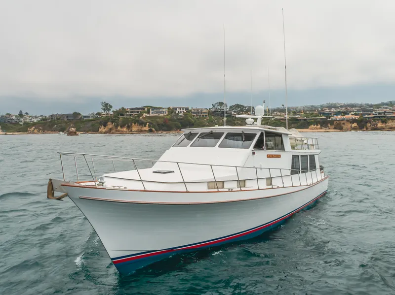 Slide: The Image of 1984 Vic Franck pilothouse yacht on the water near a coastal landscape. - 3