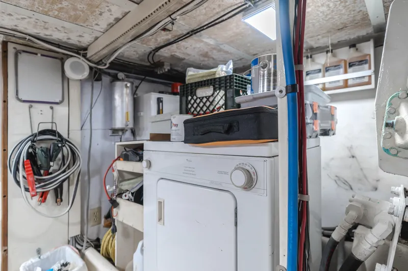 Slide: The Image of Laundry area inside a 1984 Vic Franck pilothouse, featuring a dryer and storage items. - 30