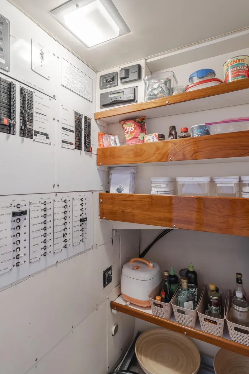 Slide: The Image of Electrical panel and organized shelves in a 1984 Vic Franck pilothouse, featuring various kitchen supplies. - 42